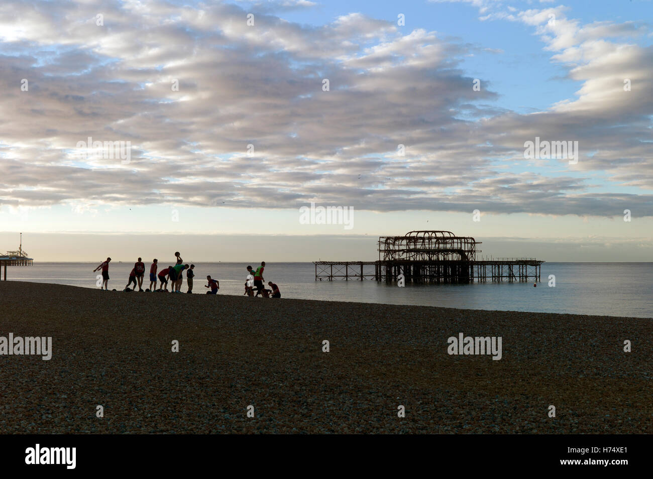 Le persone che la esercitano sulla spiaggia accanto ai derelitti Molo Ovest di Brighton, Regno Unito Foto Stock