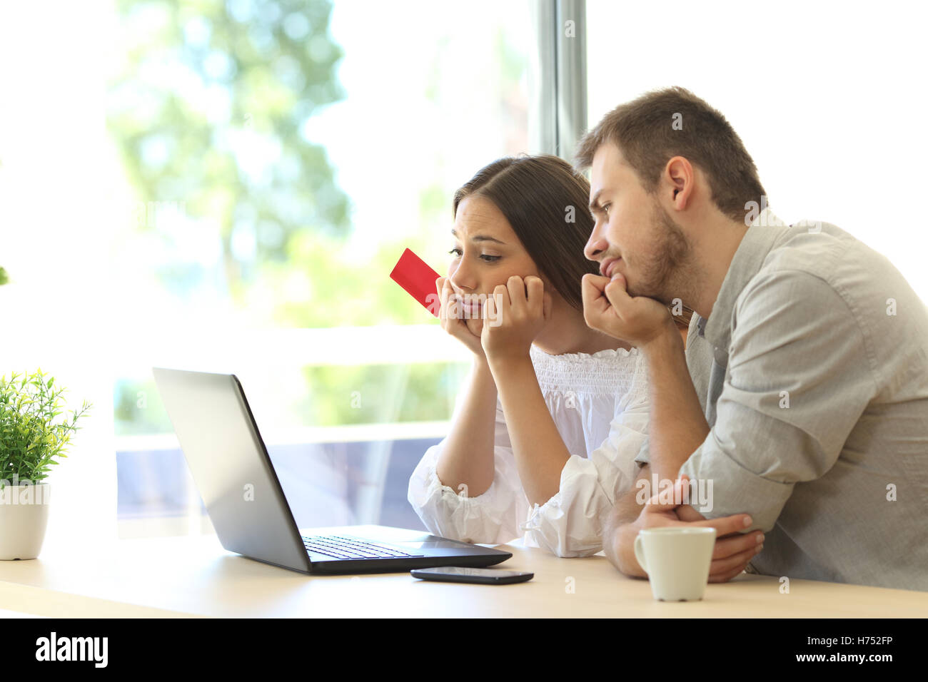 Gli acquirenti frustrati tentando di pagare online con carta di credito e un computer portatile a casa Foto Stock