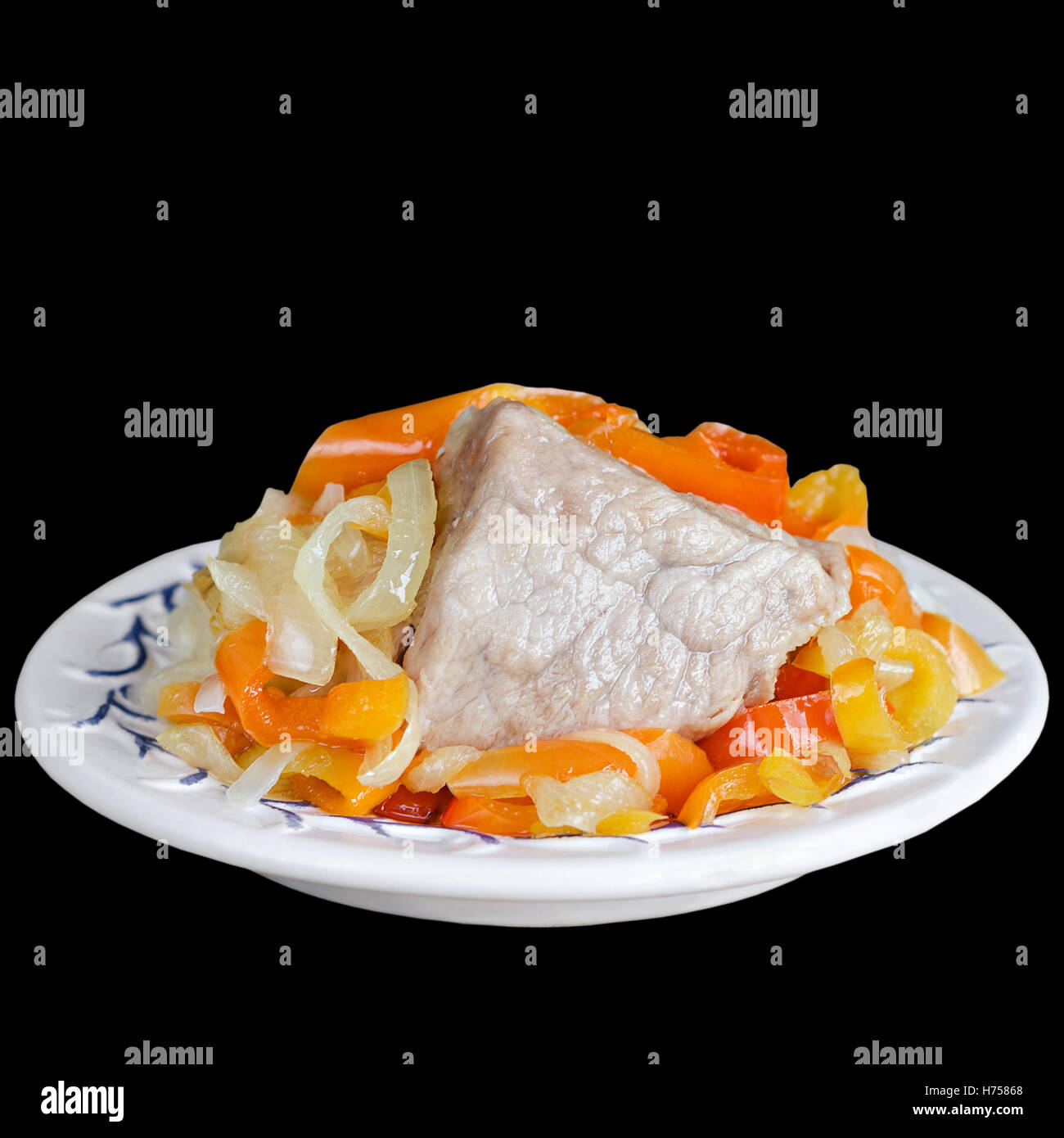 Pezzo di carne di maiale con verdure su una piastra, isolato su sfondo nero Foto Stock