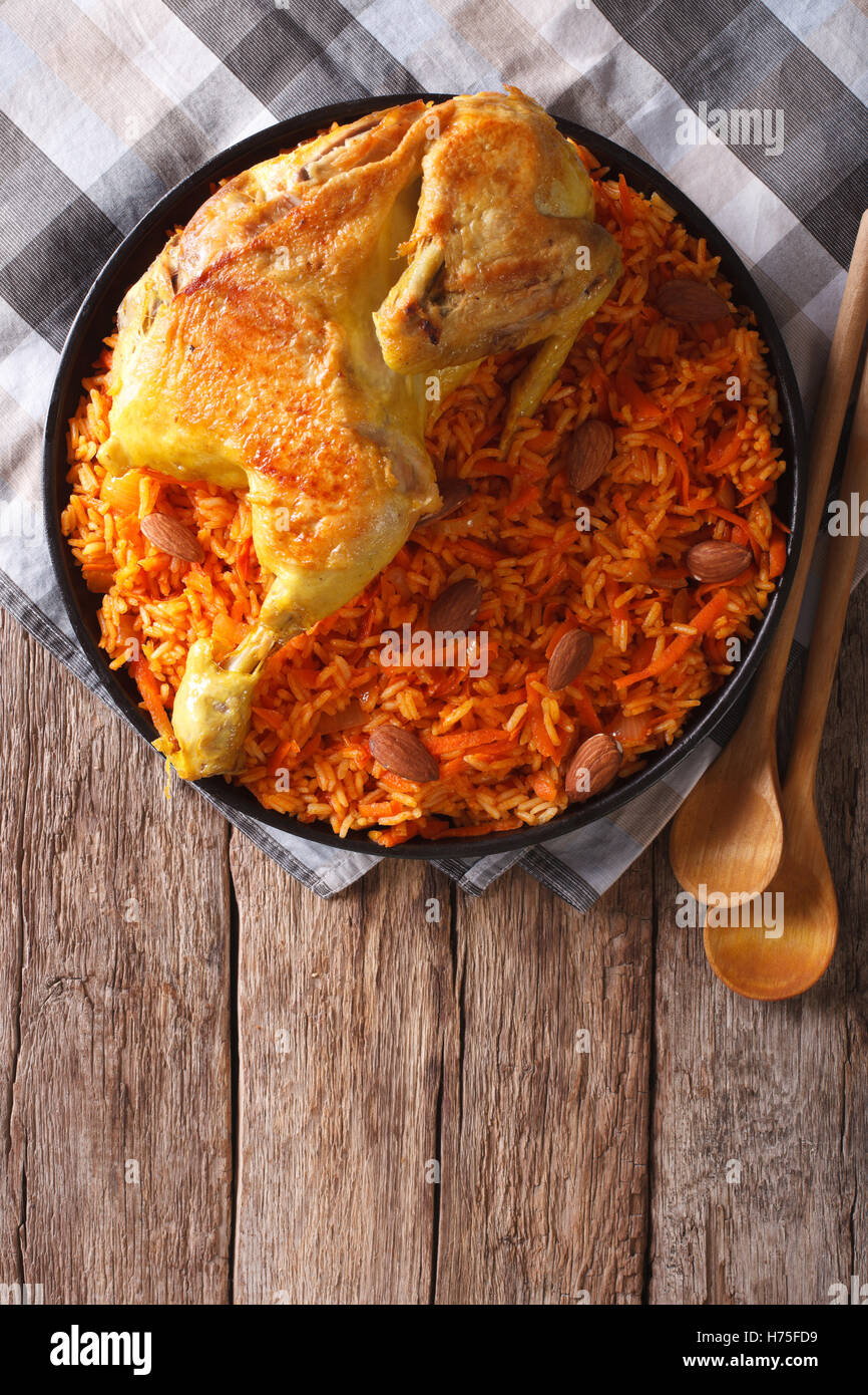 Kabsa di pollo con riso e verdure su un piatto sul tavolo. vista verticale da sopra Foto Stock