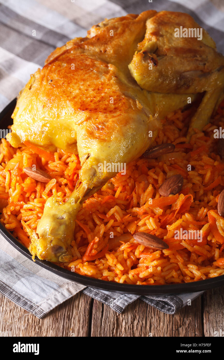 Tradizionale cibo arabo: kabsa con pollo e mandorle close-up su una piastra verticale. Foto Stock
