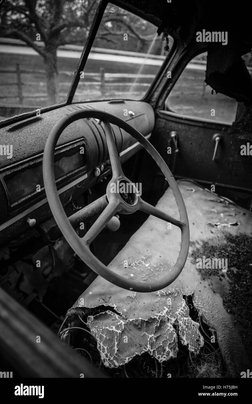 All'interno di una vecchia fattoria abbandonata carrello. Focus sul volante. In bianco e nero. Foto Stock