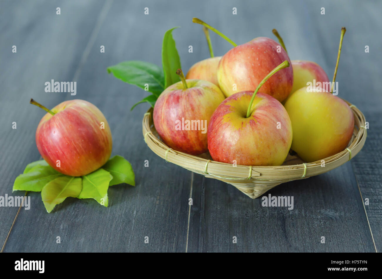 Rosso e giallo apple con cesto di bambù , organica frutta fresca su sfondo di legno Foto Stock
