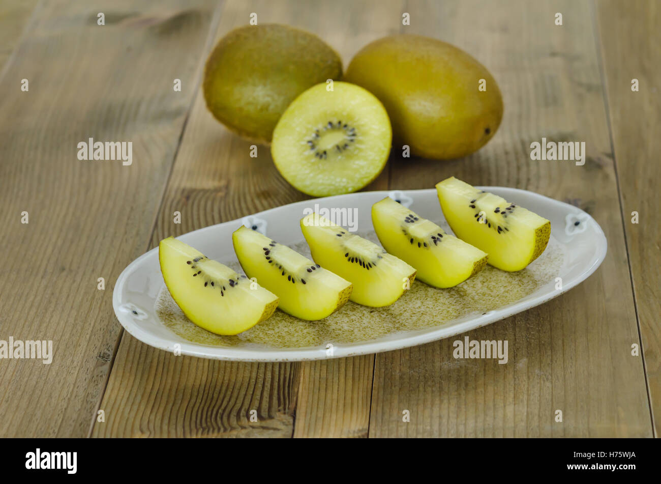 Golden kiwi e affettato sul piatto su sfondo di legno Foto Stock