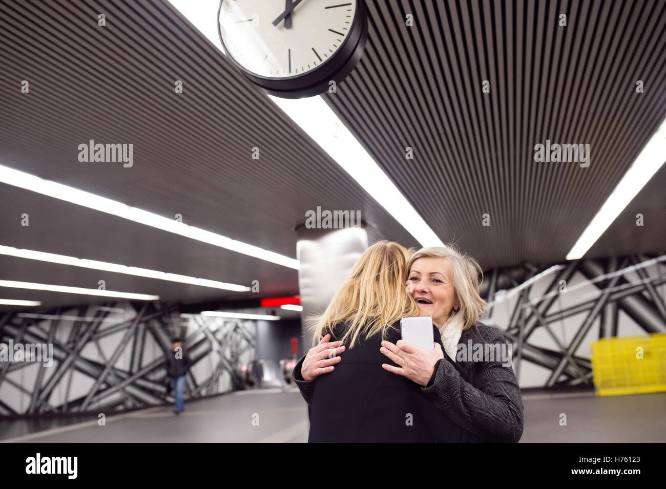 Due belle donne in piedi alla piattaforma della metropolitana, huggin Foto Stock