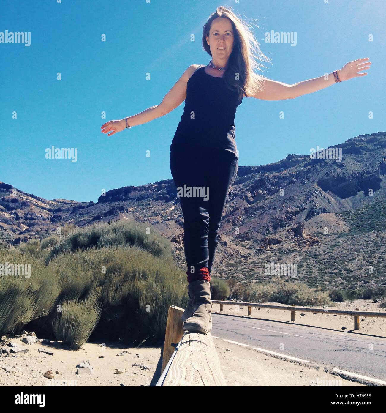 Donna che cammina lungo una recinzione Foto Stock