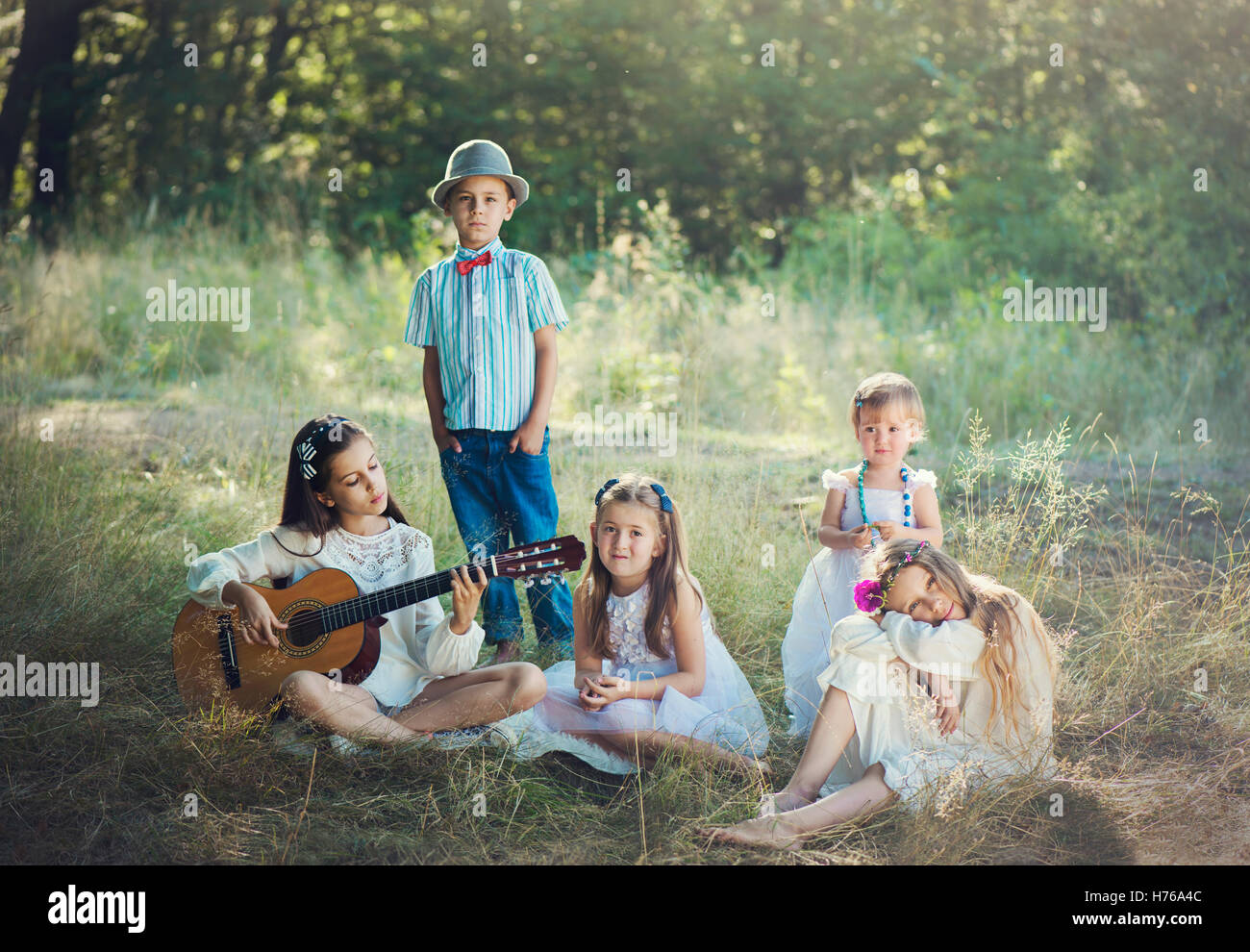 Il gruppo di cinque bambini nella foresta, uno a suonare la chitarra Foto Stock