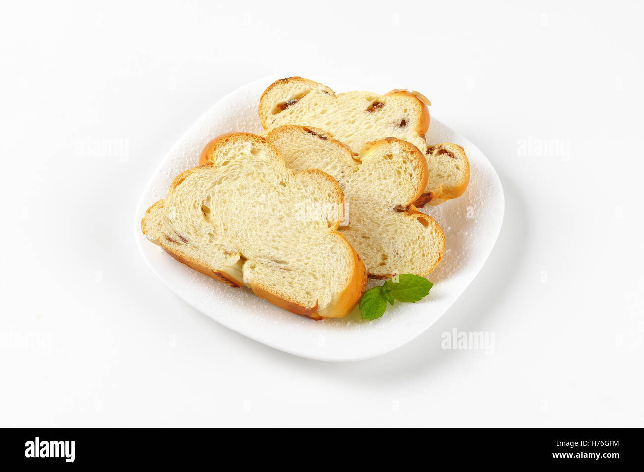 Fette di dolce pane intrecciato su piastra bianca Foto Stock