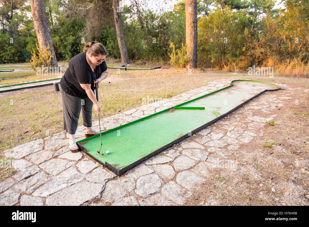 Donna che gioca outdoor golf in miniatura in una foresta di Galilea nel nord di Israele Foto Stock