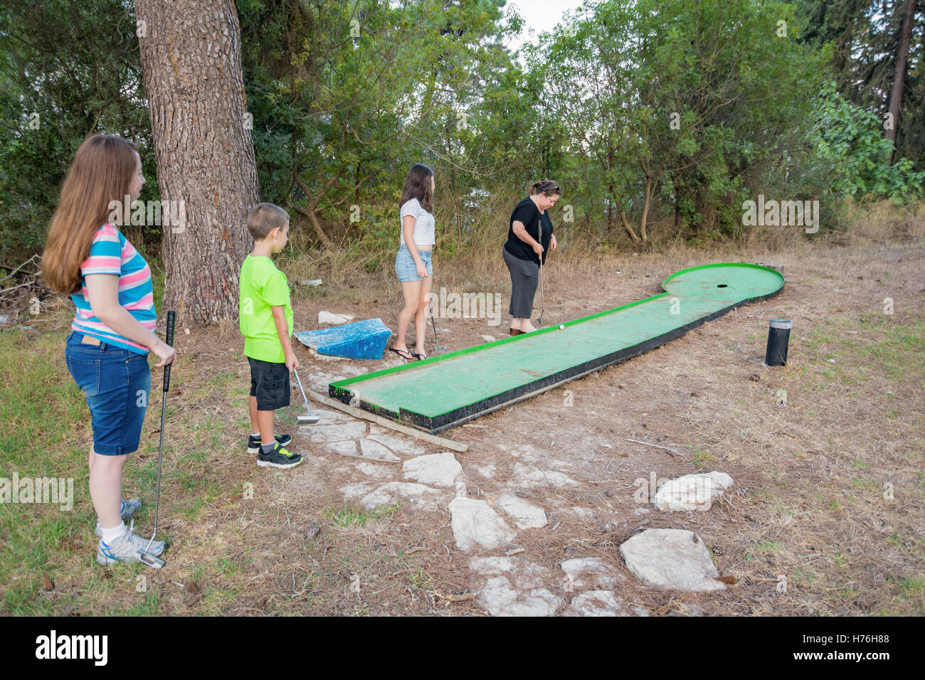 Madre e tre bambini che giocano outdoor golf in miniatura in una foresta di Galilea nel nord di Israele Foto Stock