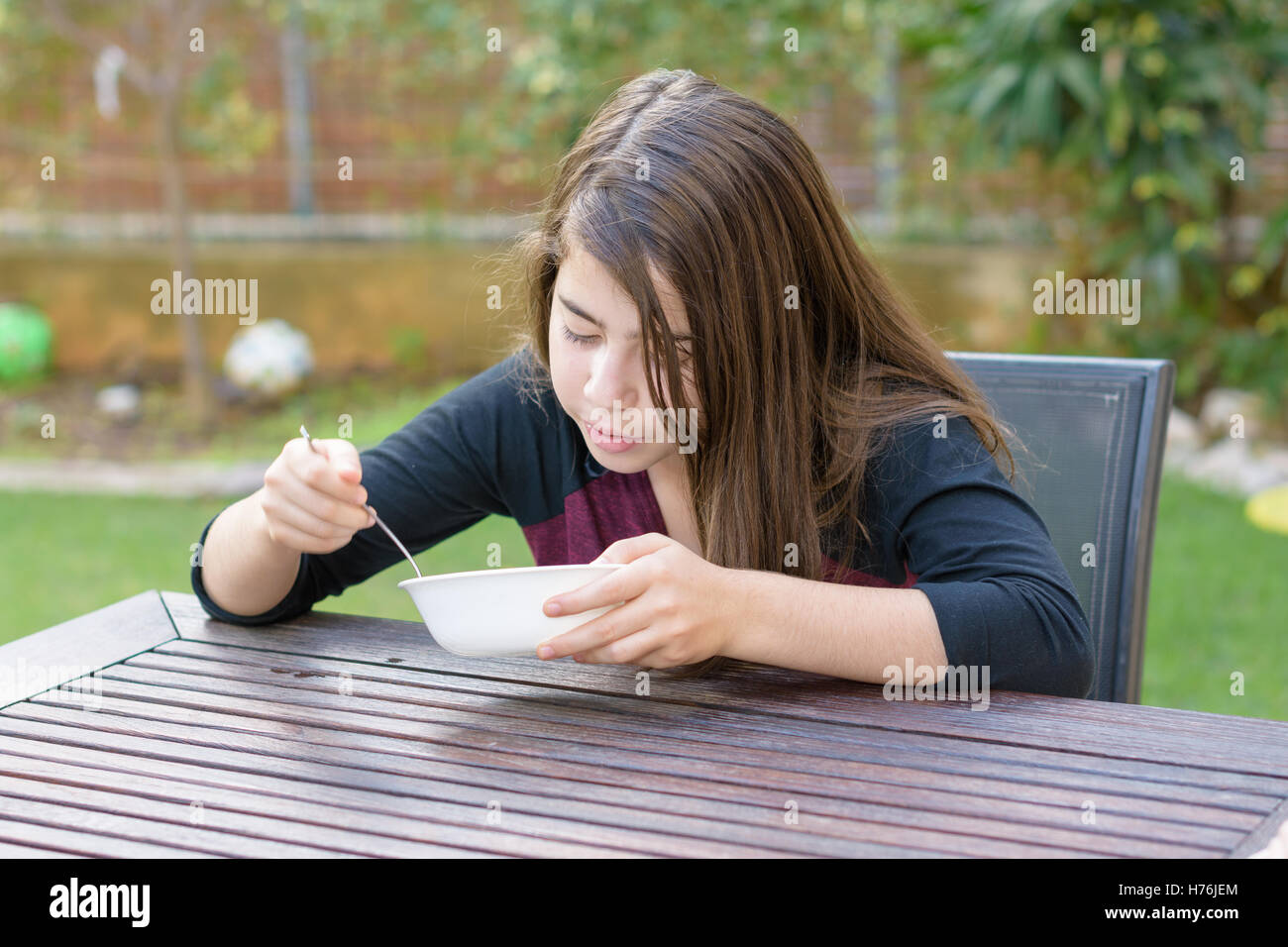 Una ragazza adolescente con rinforzi su i suoi denti godendo di calda zuppa di pollo (a.k.a. la penicillina ebraica) in una fredda giornata autunnale Foto Stock