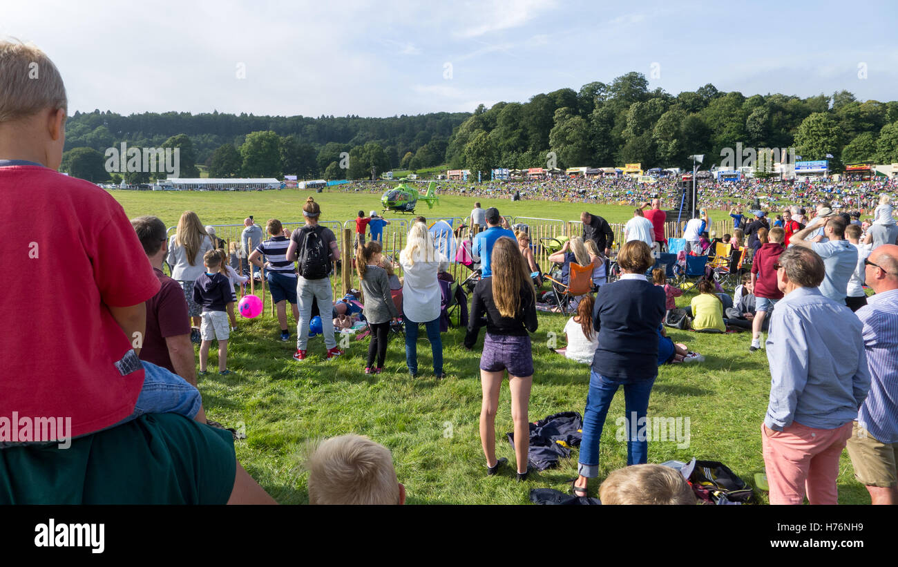 La folla di persone che guardano un elicottero in un campo Foto Stock