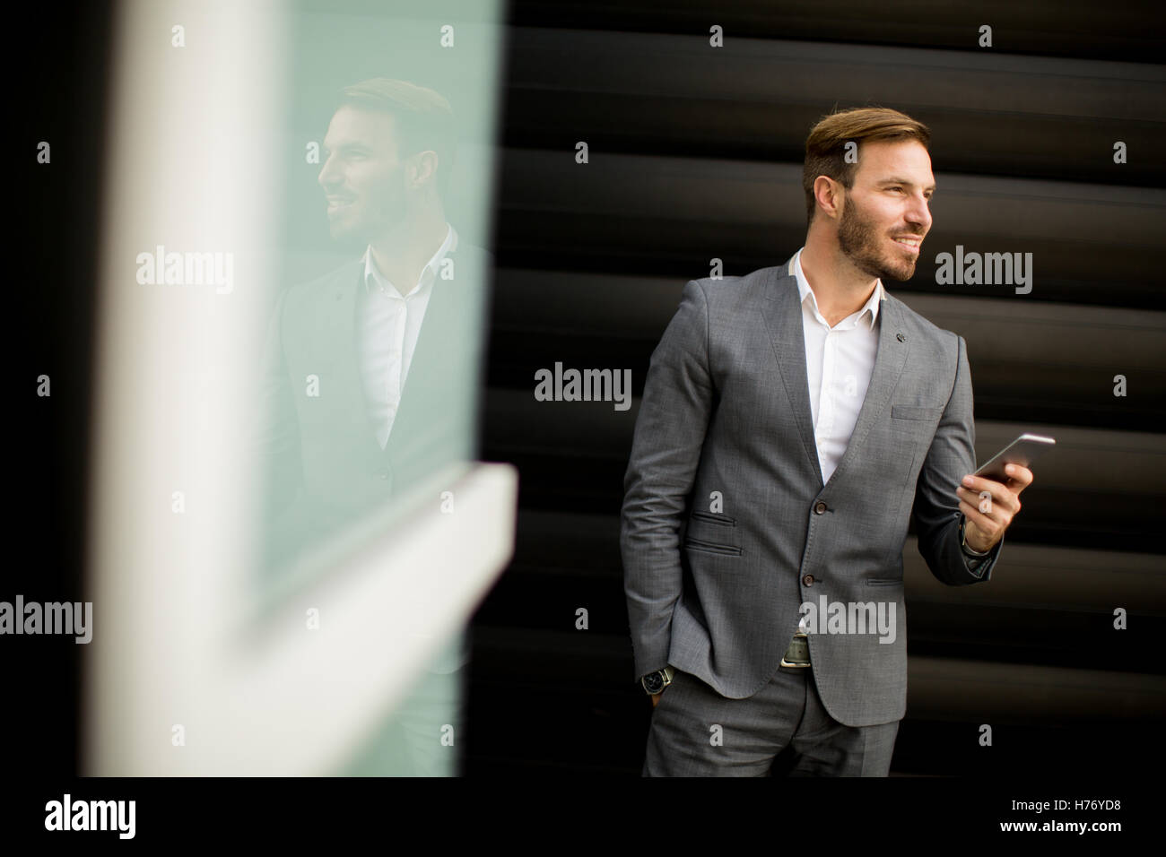 Imprenditore con un telefono dal muro nero Foto Stock