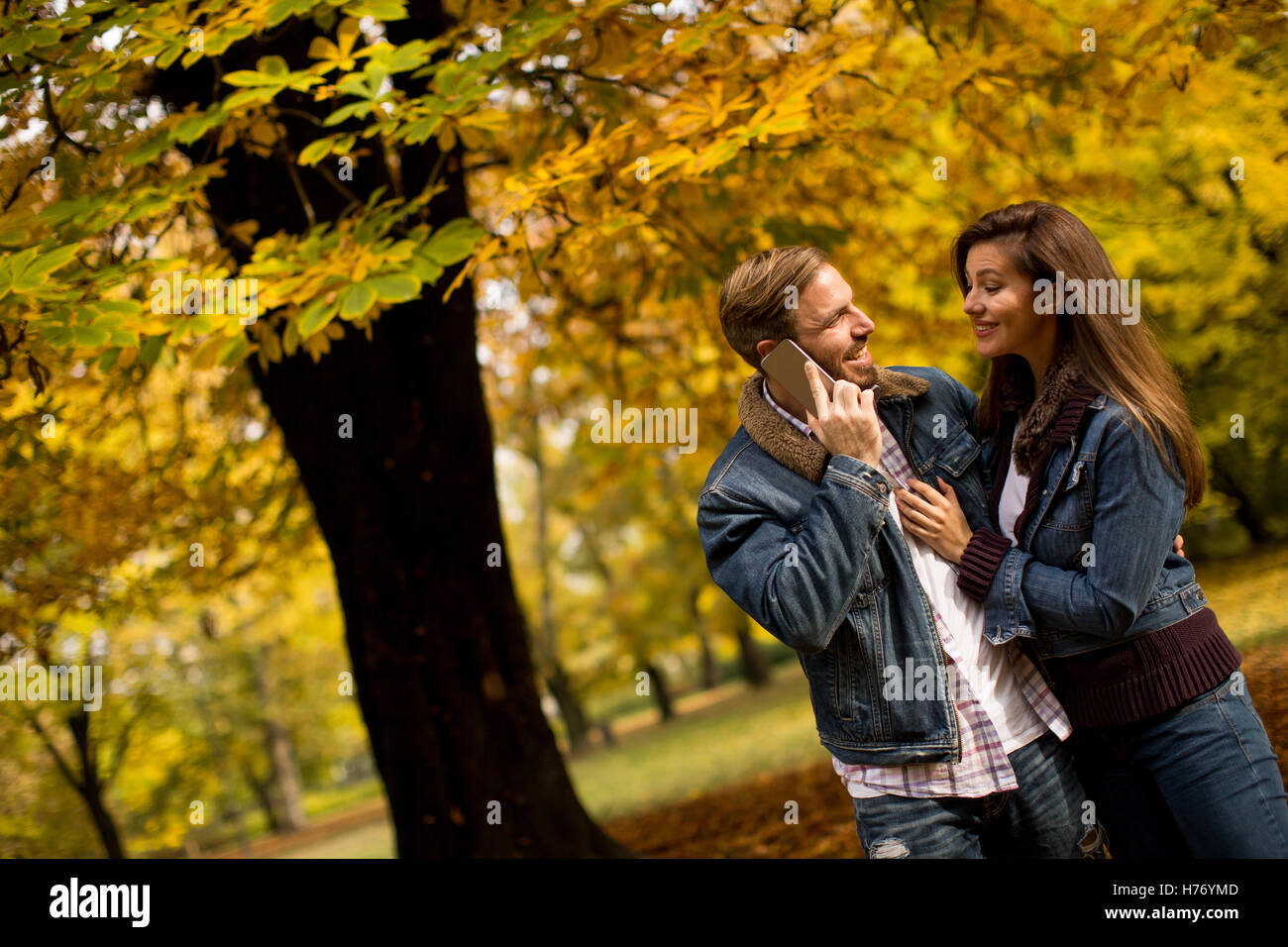 Amorevole coppia giovane in autunno park e uomo che parla al telefono Foto Stock
