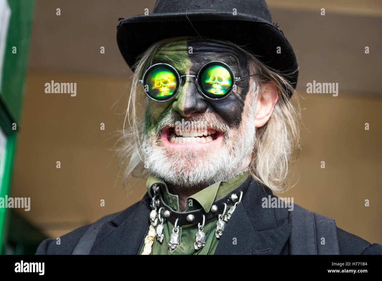 Scope di mattoni e giocatori Border Morris l'uomo. Johnny Morris, il volto dipinto di nero e verde, indossa gli occhiali da sole di ologramma, maniaco espressione. Face shot. Foto Stock