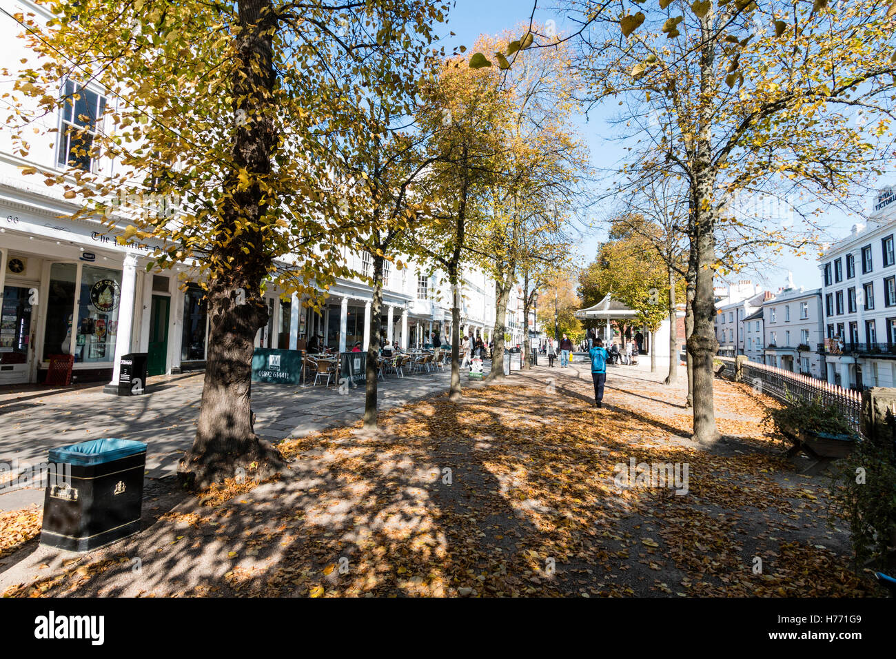 Inghilterra, Tunbridge Wells. Il famoso Pantiles in autunno. Vista lungo viale alberato area aperta coperto di foglie cadute, con palco per spettacoli in background. Foto Stock