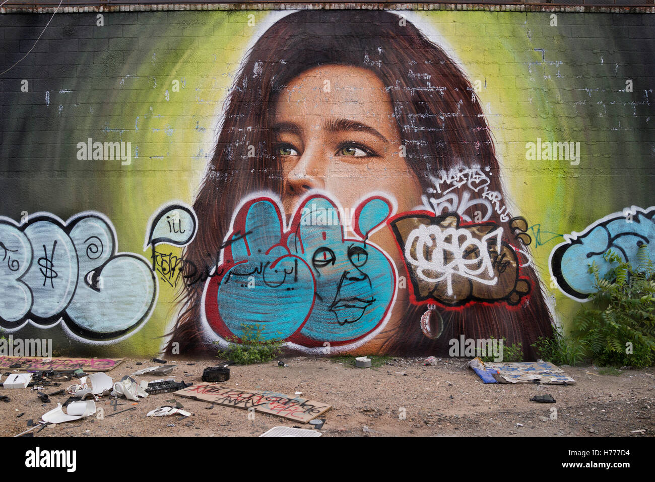 Muro di graffiti murali di arte di strada lungo Meserole St in Oriente Williamsburg / Brunswick sezione di Brooklyn, New York City, USA pneumatici impilati, & garbage Foto Stock