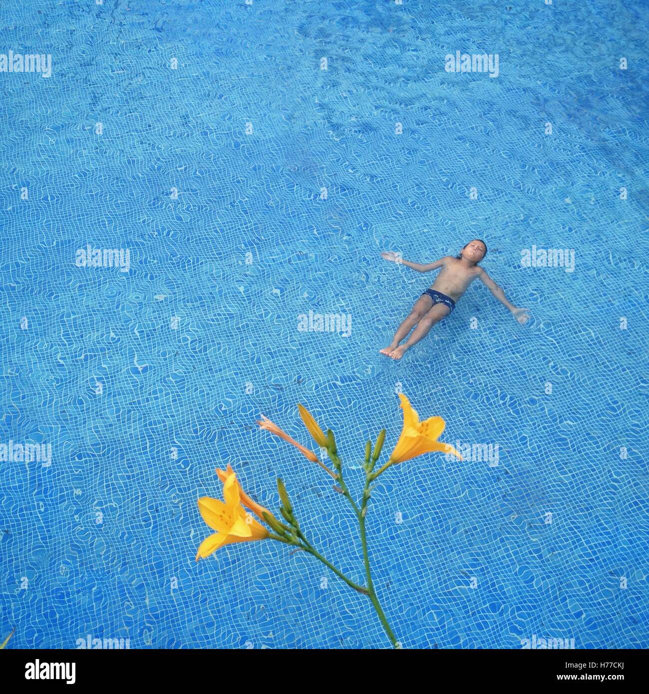 Ragazzo giacente in una piscina con un fiore Foto Stock