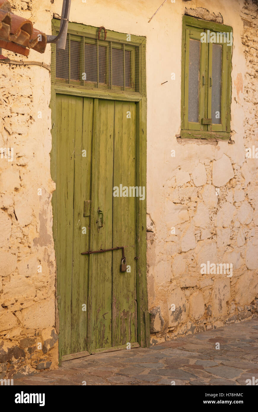 Vecchio legno verde porta con cerniere arrugginito all'ingresso di Cipro vecchia casa di pietra. Villaggio Lazanias. Cipro. Foto Stock