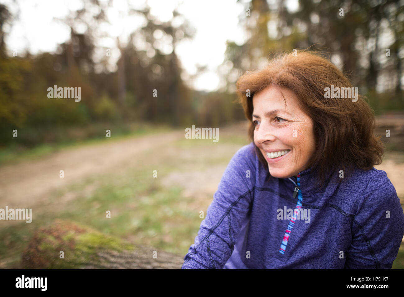 Senior runner seduti su tronchi di legno, donna in appoggio, sorridente. Foto Stock