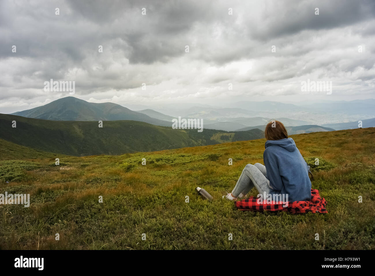 Ragazza di riposo in montagna. Persona di sesso femminile sedersi e godersi la splendida vista del paesaggio di montagna in un giorno nuvoloso Foto Stock