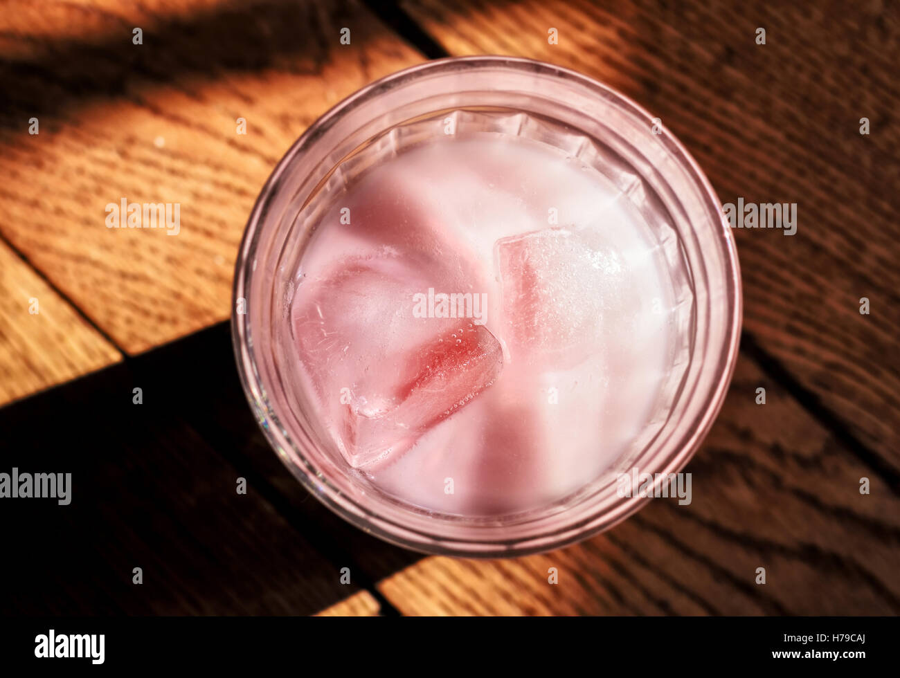 Rosa di yogurt con ghiaccio in vetro sul pavimento in parquet Foto Stock