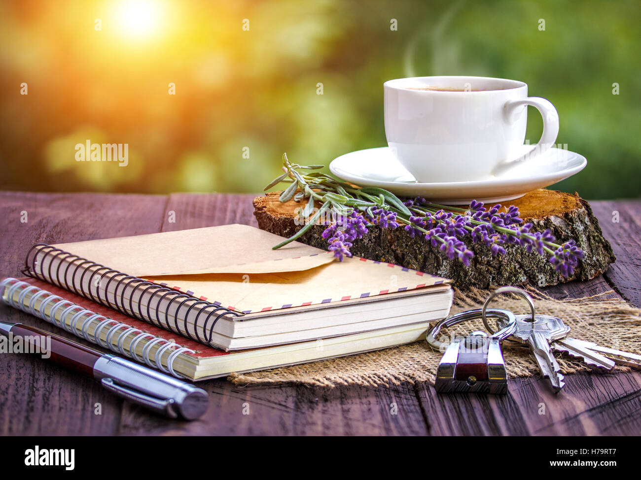Vuoto notebook bianco,le chiavi, mazzetto di lavanda e tazza di caffè sulla scrivania all'aperto in estate Foto Stock