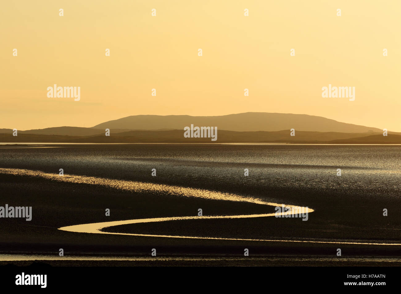 Malacleit bay North Uist Ebridi Esterne della Scozia UK una nebbiosa color pesca bagliore del tramonto riflesso nel fango con la bassa marea Foto Stock