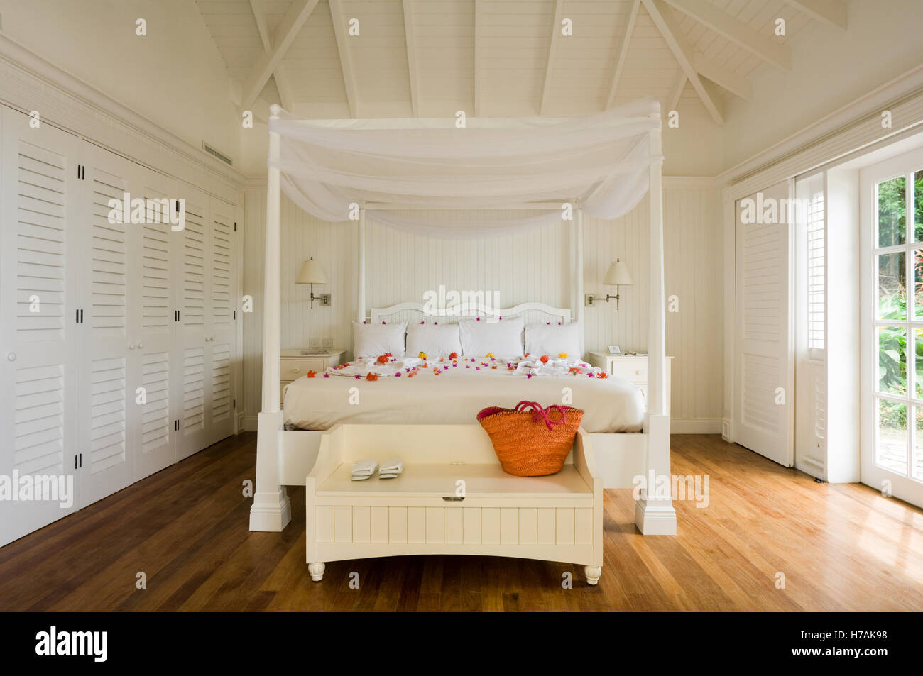Bianco quattro postered bed sparse con petali di fiori in St Lucia home, dei Caraibi Foto Stock