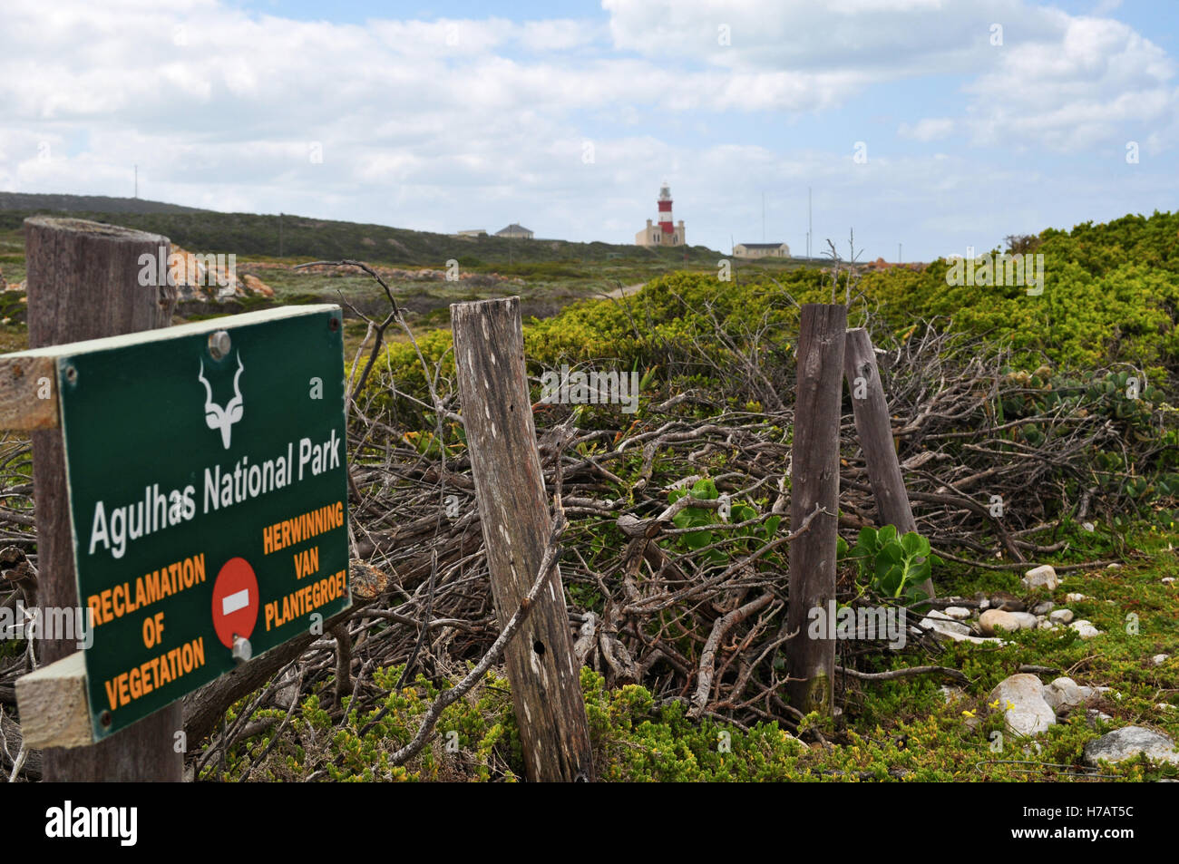 Sud Africa: il Cape Agulhas Faro, costruito nel 1849 sul bordo meridionale del villaggio di L'Agulhas, con il segno del Agulhas National Park Foto Stock