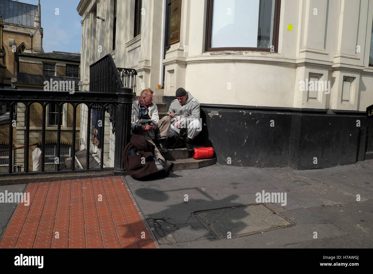 Due senzatetto amico seduto sui gradini al di fuori di una casa. Foto Stock