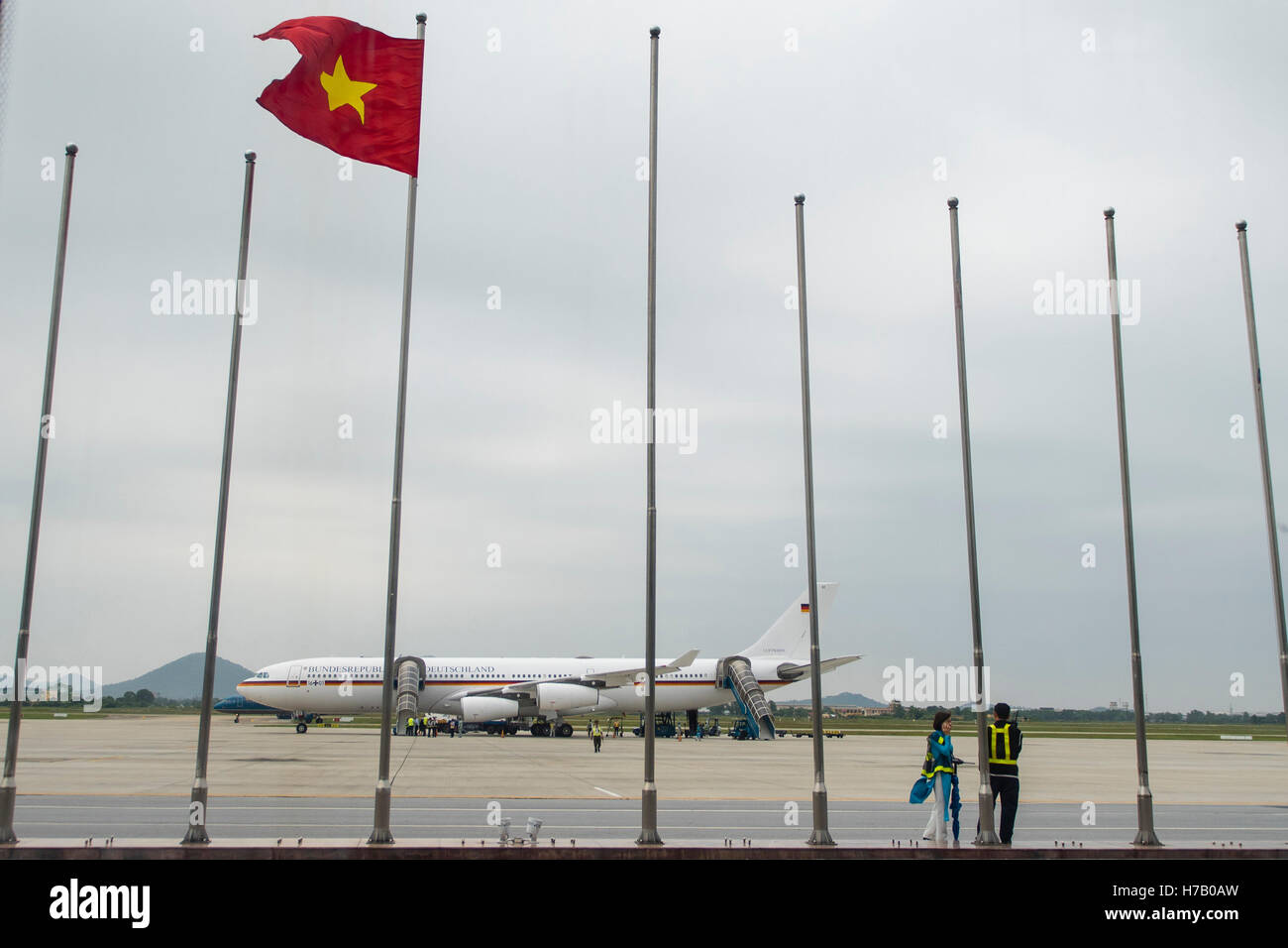 Hanoi, Vietnam. 30 ott 2016. L'Airbus A340 "Konrad Adenauer' della tedesca Air Force può essere visto all'Aeroporto Noi Bai di Hanoi, Vietnam, 30 ottobre 2016. La bandiera vietnamita onde su un palo in primo piano. Foto: GREGOR FISCHER/dpa/Alamy Live News Foto Stock