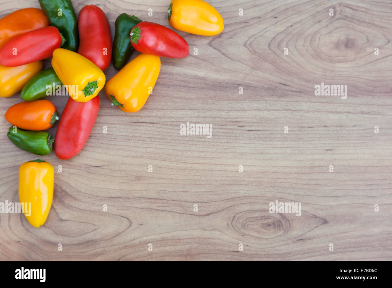 Carni rosse, verdi e le arance peperoncino (capsicum) su sfondo di legno con spazio di copia Foto Stock