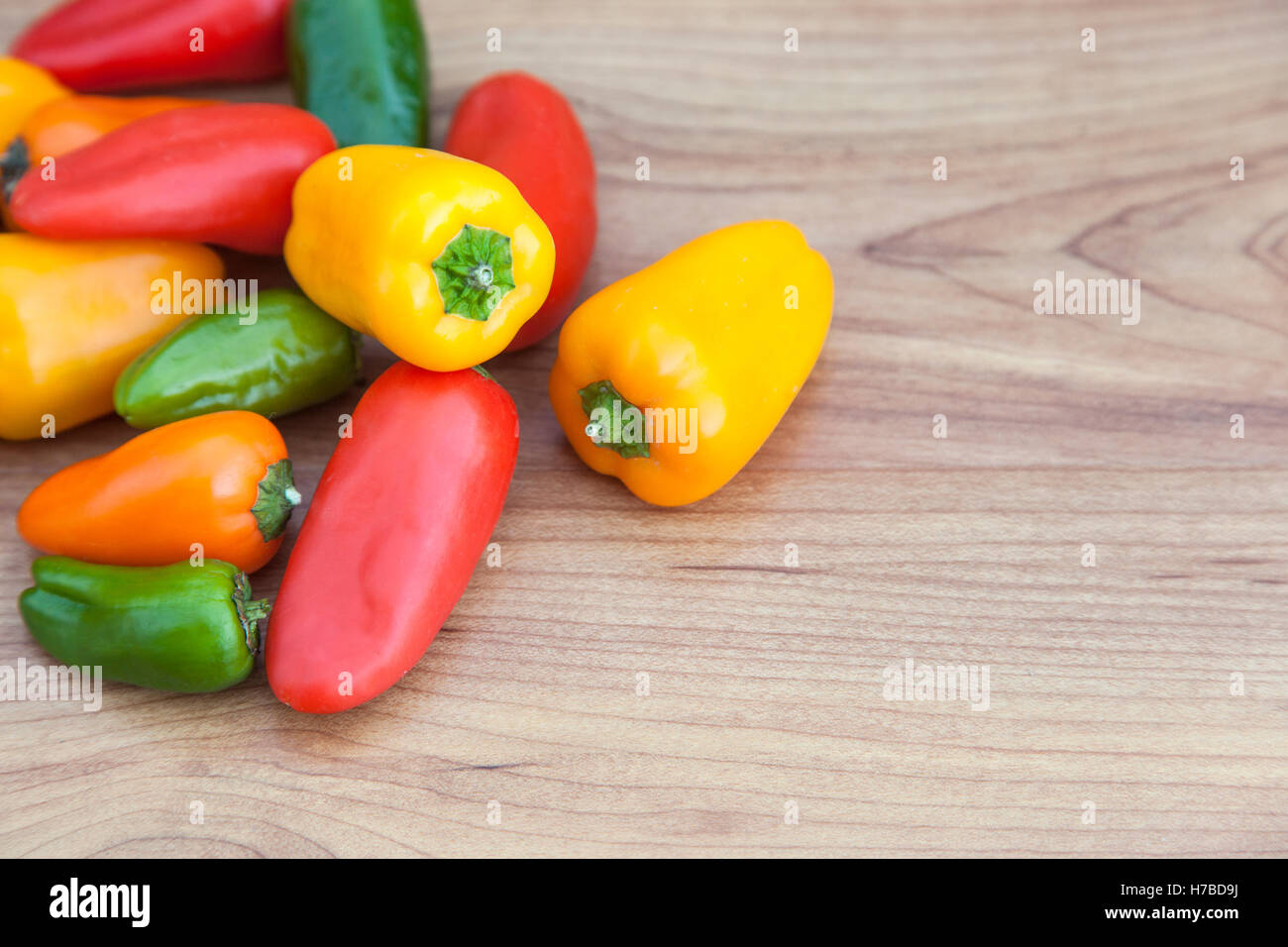 Fresh rosso, verde, giallo e arancio peperoncino (capsicum) su sfondo di legno con spazio di copia Foto Stock