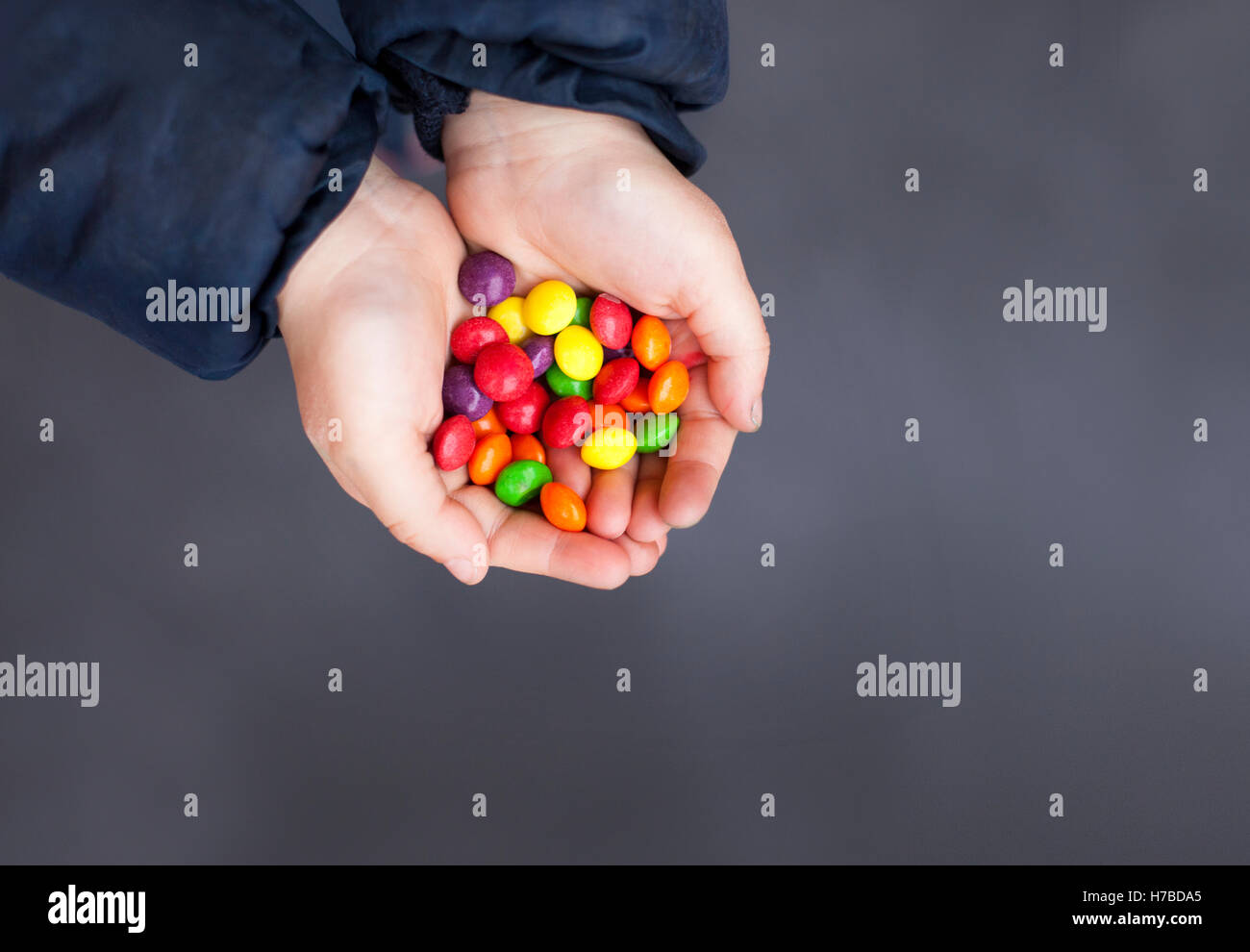 Kid le mani piene di dolci caramelle multicolori . Lo sfondo scuro e copia di spazio. Foto Stock