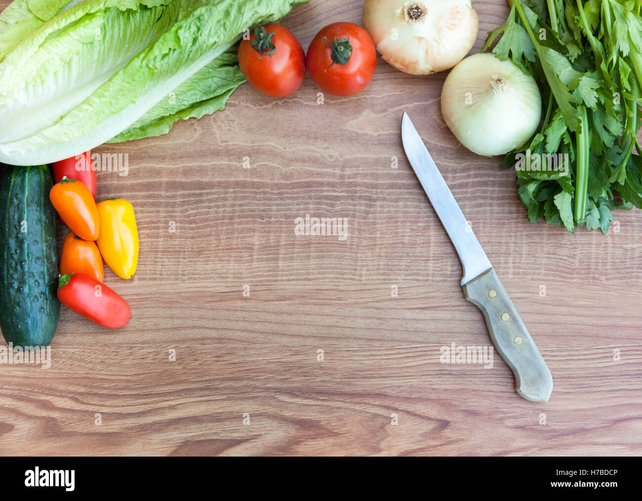 Ortaggi freschi (pomodori, peperoni, cipolle, cetrioli, lattuga e sedano) con il coltello sul taglio di legno cinghiale Foto Stock