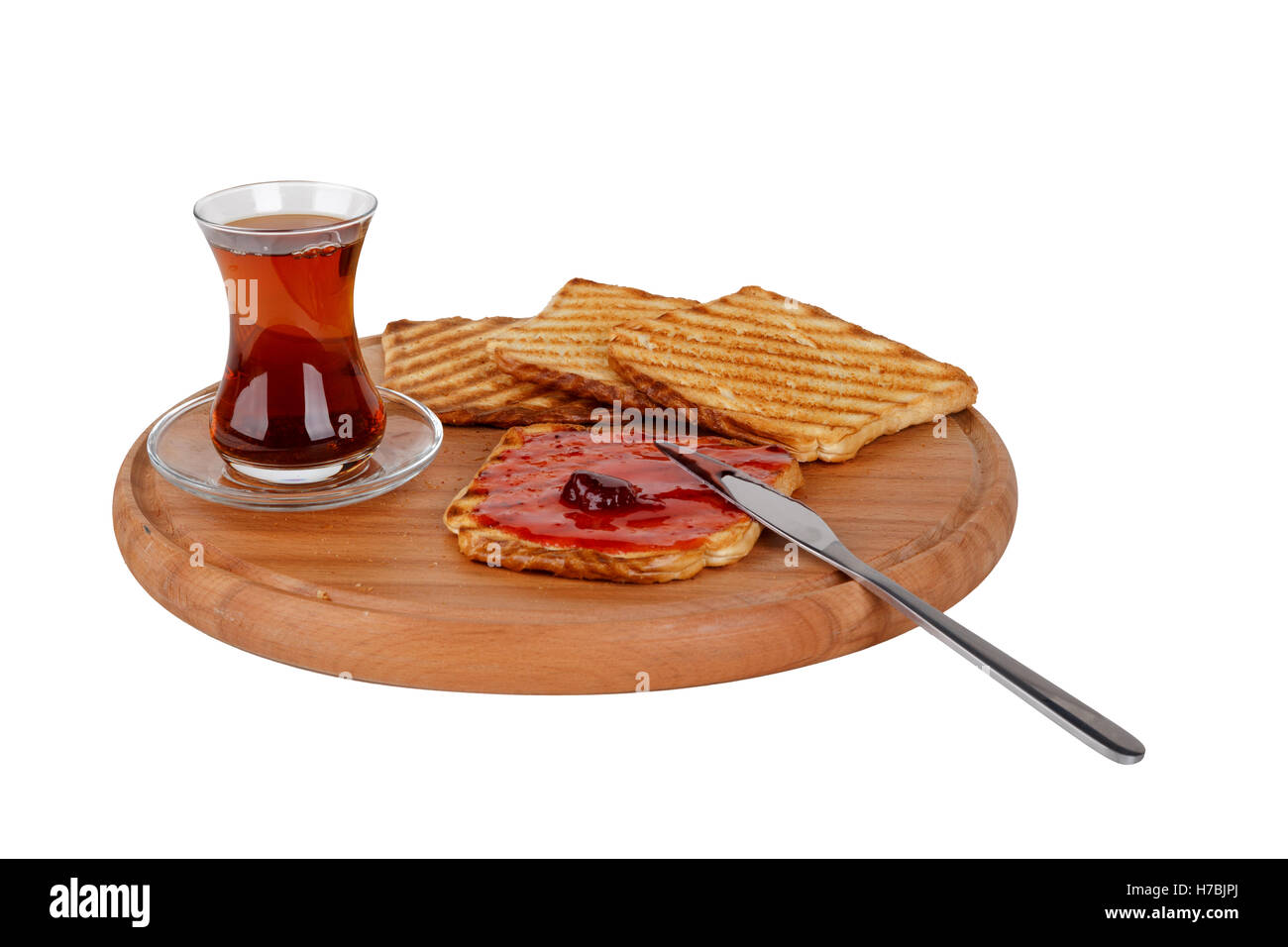 Vista laterale del bruciato pane tostato con marmellata e tè sulla tavola di legno, isolato su sfondo bianco. Foto Stock