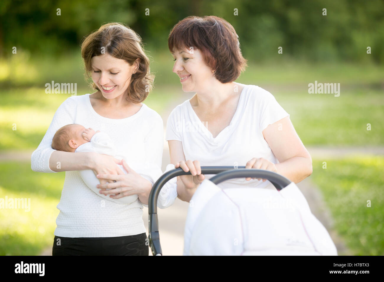 Madre e nonna passeggiate nel parco con il nuovo nato neonato Foto Stock