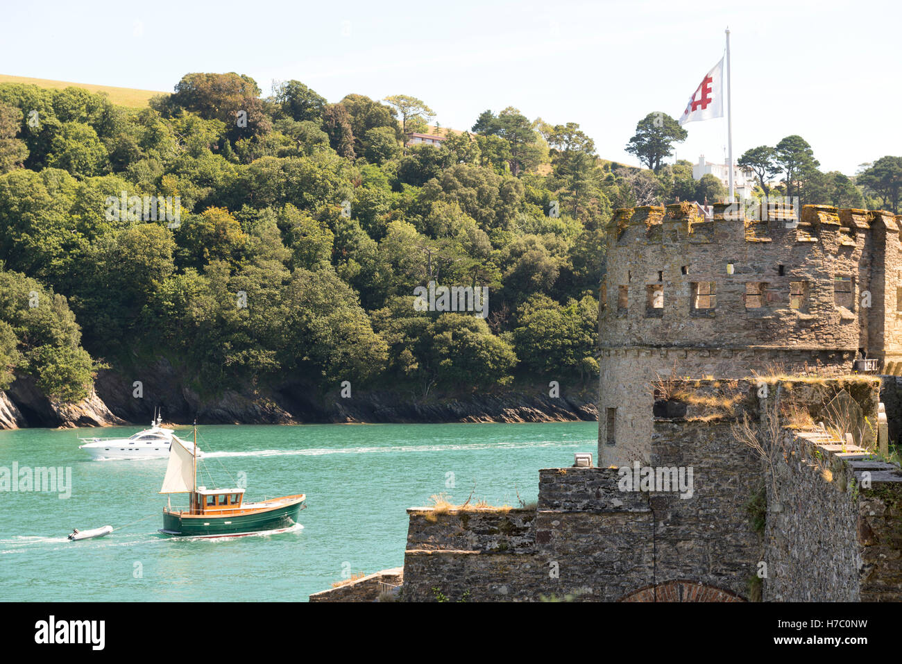 Piccola imbarcazione a motore chugs fuori in mare sul fiume Dart passando dartmouth castle in primo piano battenti english heritage flag. Foto Stock