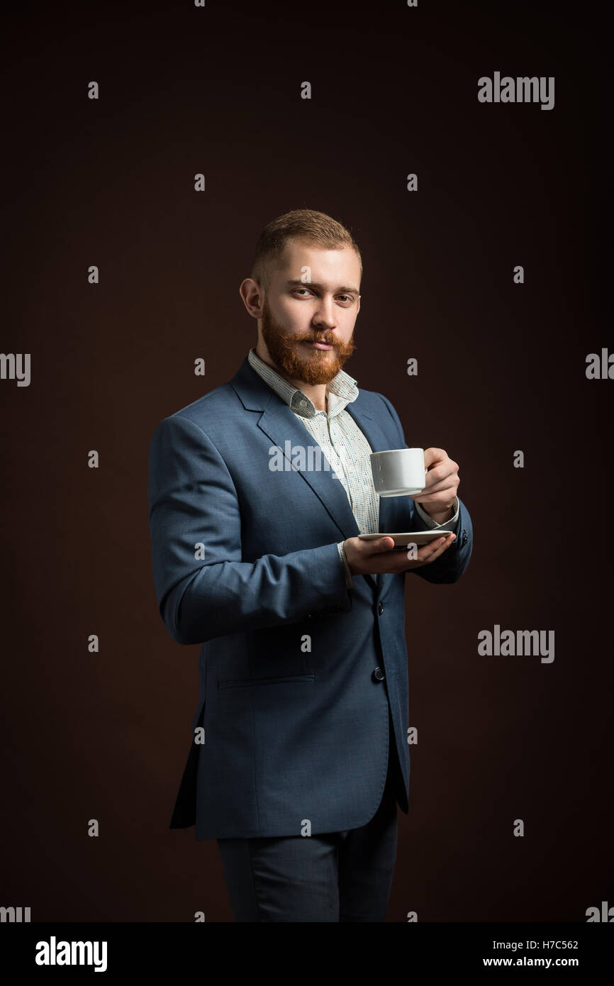 Elegante uomo barbuto con tazza di caffè Foto Stock