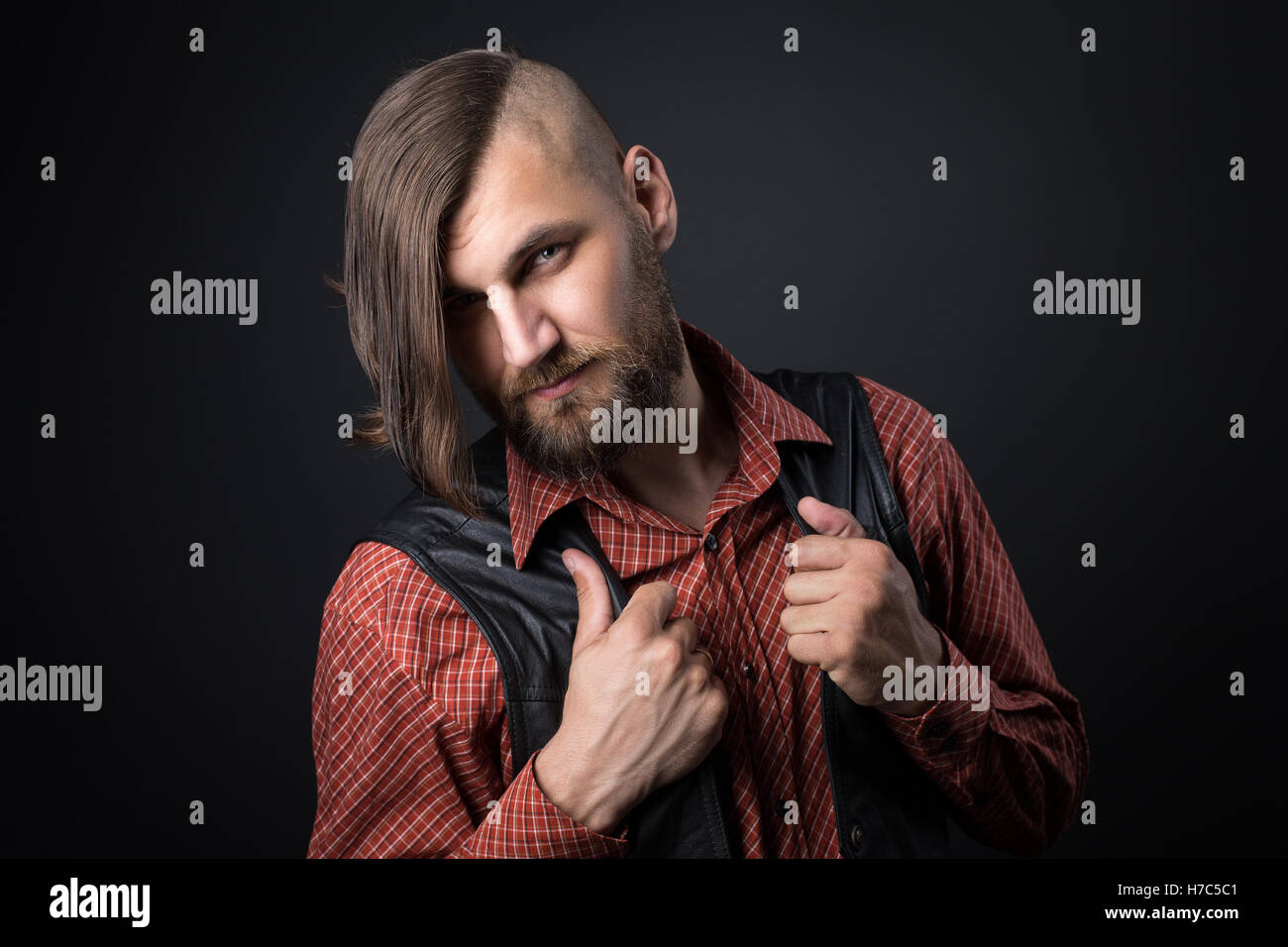 Uomo Barbuto detiene sul suo gilet e guardando la telecamera Foto Stock