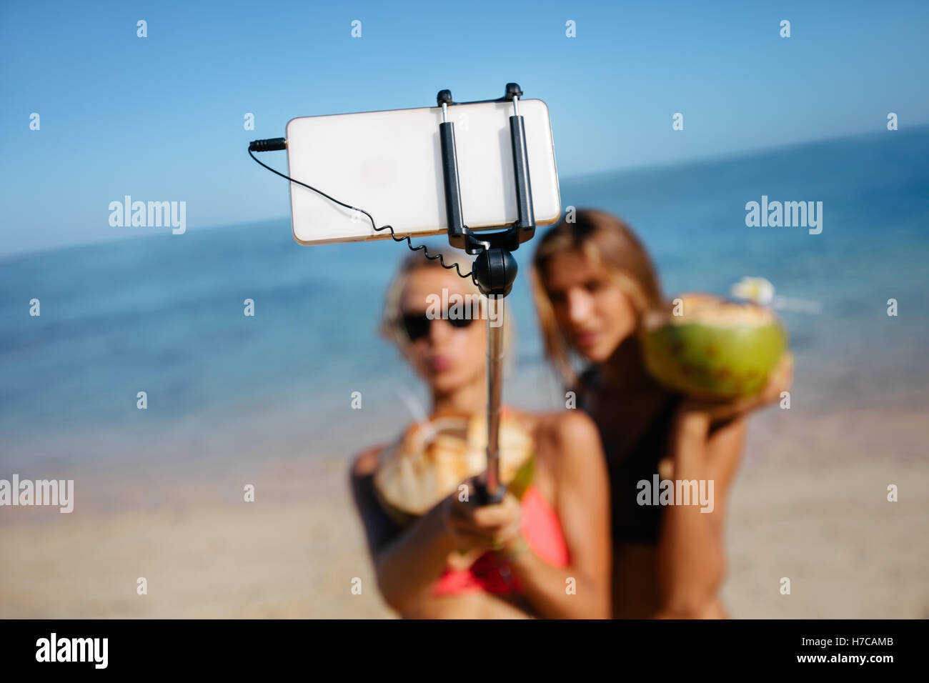 Due giovani amici di sesso femminile prendendo autoritratto con lo smartphone sulla spiaggia. Le donne in vacanza sulla spiaggia prendendo selfie. Focus su mobil Foto Stock