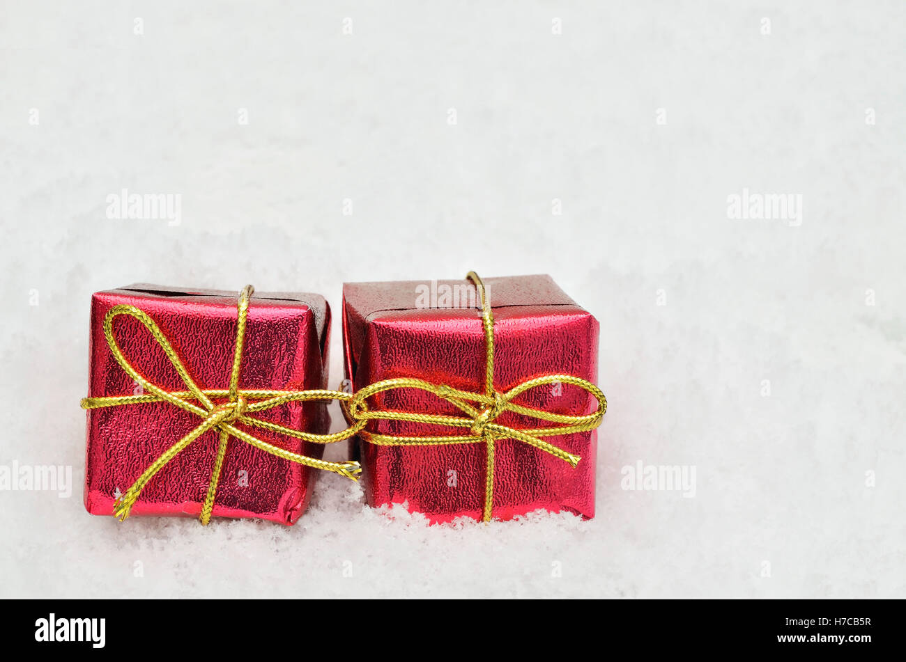 Due piccoli rosso metallico parcelle luminoso sulla neve sfondo, vicino, spazio per il testo, orizzontale Foto Stock