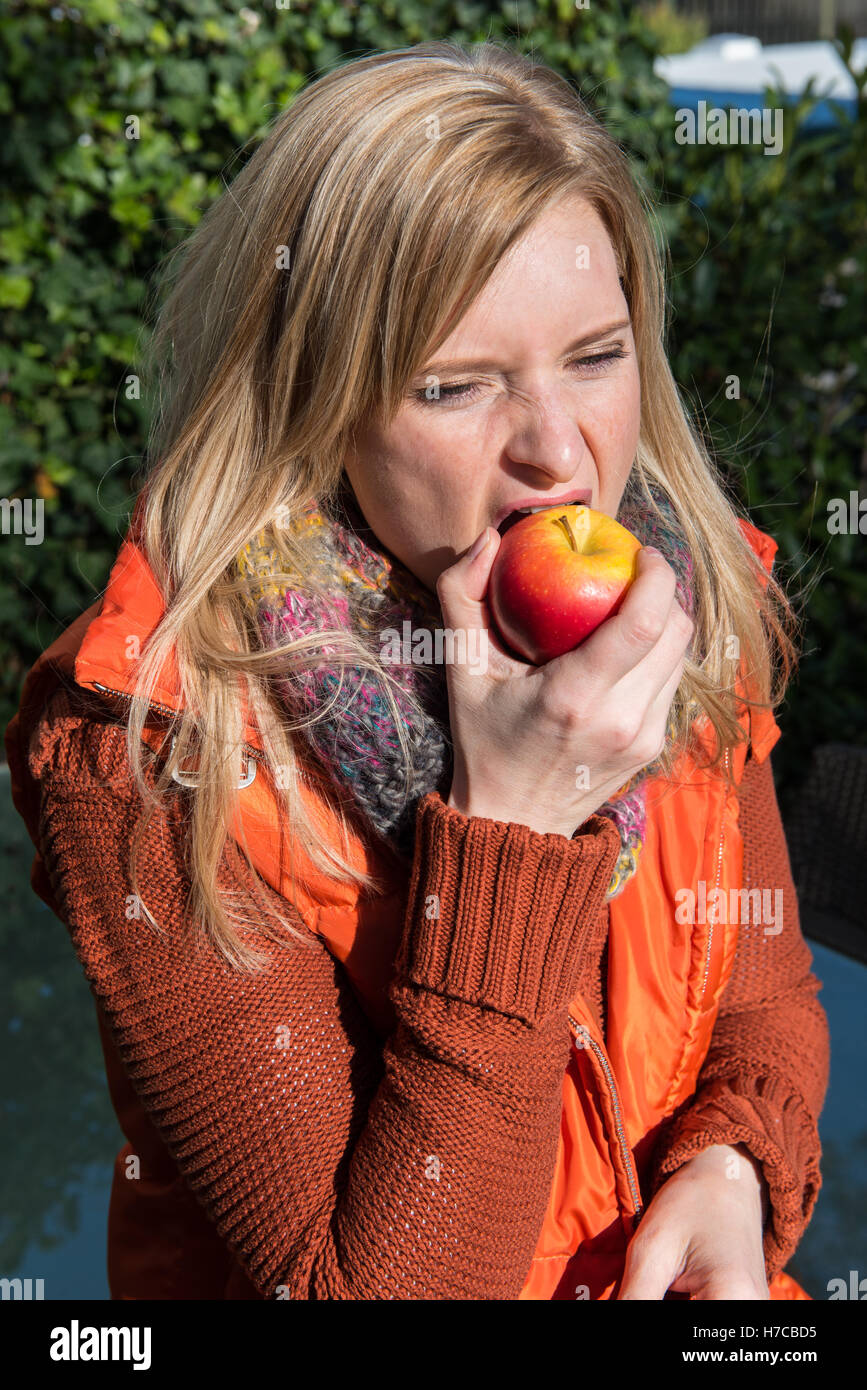Attraente donna bionda di mordere in un Apple Foto Stock