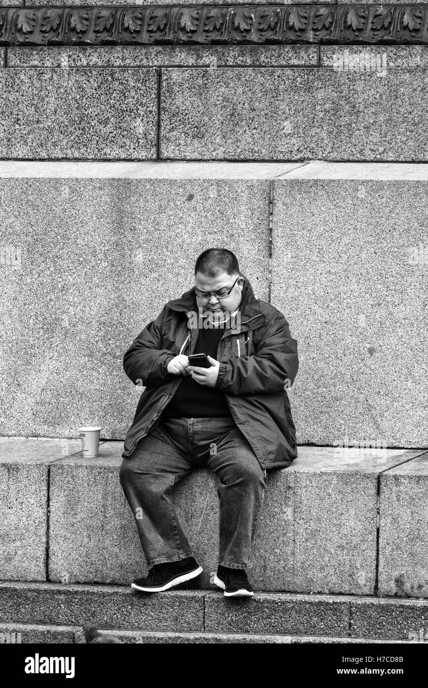 Prendendo una pausa per sfogliare il suo smartphone in George Square Glasgow Scotland Regno Unito Foto Stock