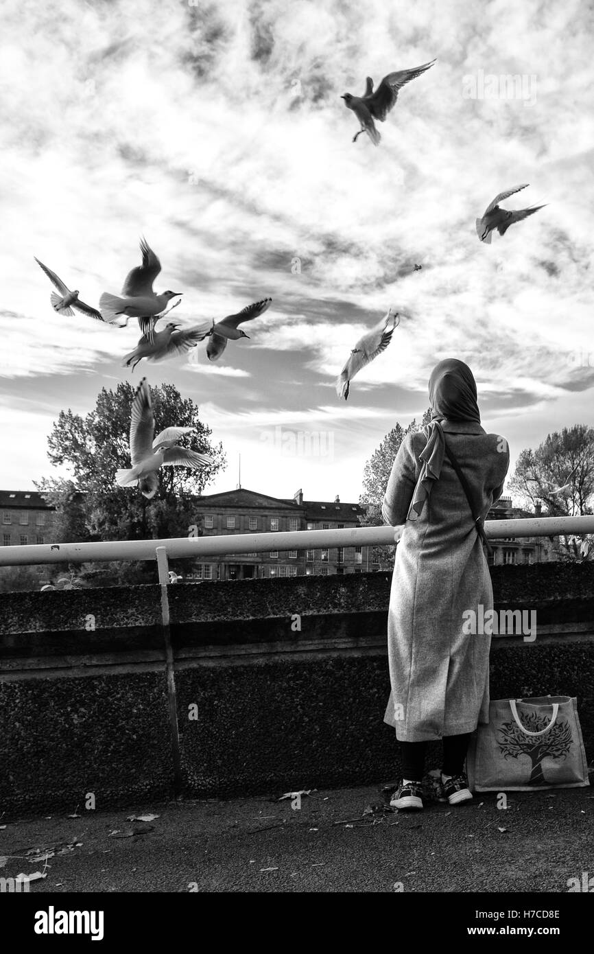 Una donna di alimentare gli uccelli su di Glasgow Clyde lato su un freddo inverno mattina Foto Stock