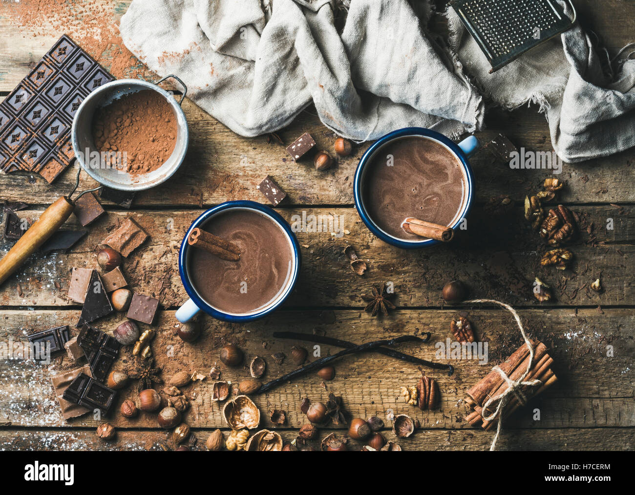 Cioccolata calda con bastoncini di cannella, anice, dadi e cacao in polvere di legno rustico sfondo, vista dall'alto, composizione orizzontale Foto Stock