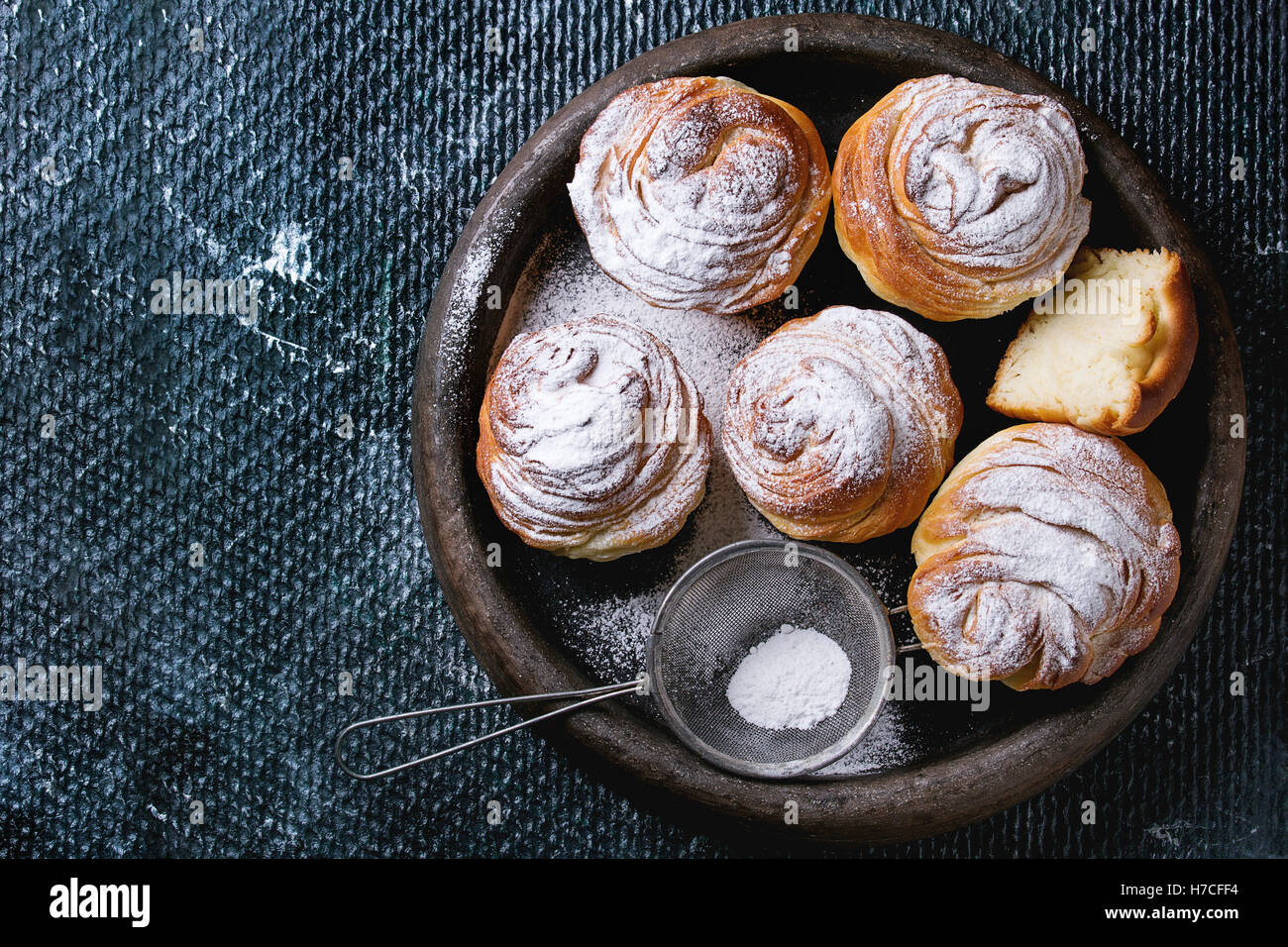 Pasticceria moderna cruffins interi e slice, come croissant e muffin con lo zucchero in polvere, servita nel vassoio di argilla con vintage o del crivello inferiore Foto Stock