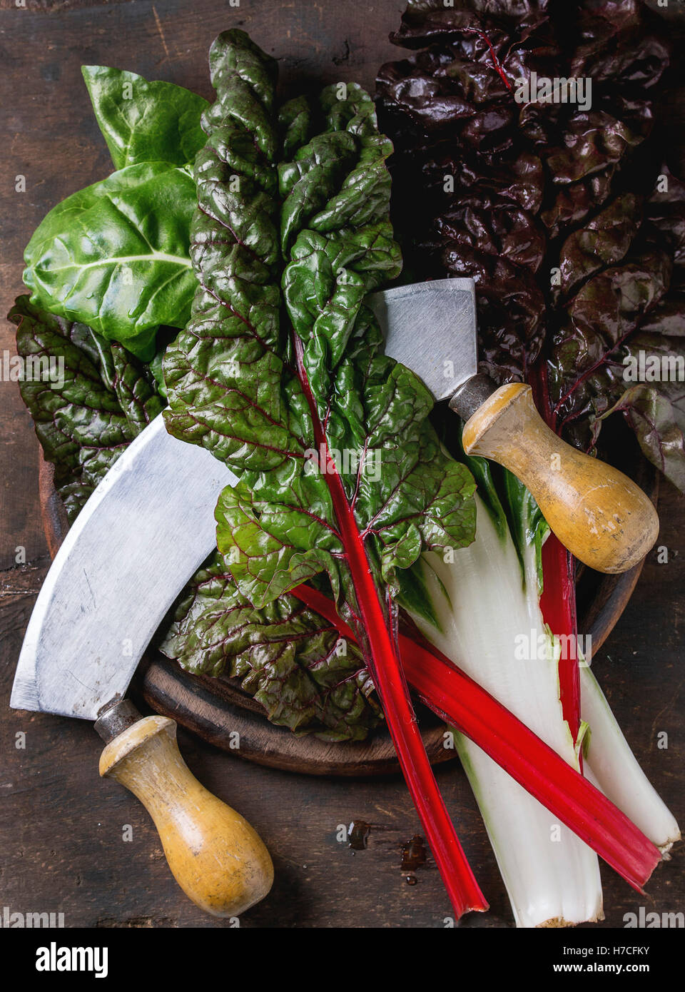 Varietà di bietole novelle mangold foglie di insalata woode sul tagliere con coltello vintage su un vecchio legno scuro dello sfondo. Vista superiore Foto Stock