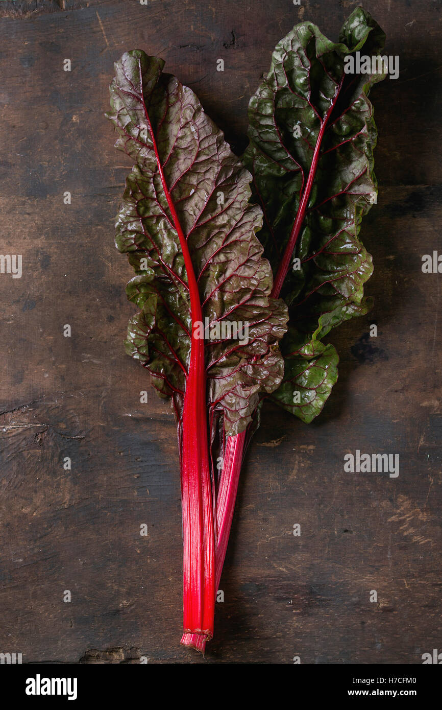 Bietole novelle mangold foglie di insalata su un vecchio legno scuro dello sfondo. Vista da sopra con spazio per il testo. Mangiare sano tema. Foto Stock